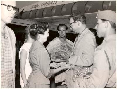 Dave Brubeck receiving bouquet upon arrival at airport, Joe Morello in foreground, and unidentified security personnel in front of airplane (Baghdad, Iraq)