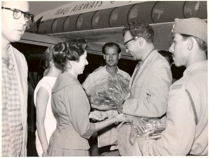 Dave Brubeck receiving bouquet upon arrival at airport, Joe Morello in foreground, and unidentified security personnel in front of airplane (Baghdad, Iraq)