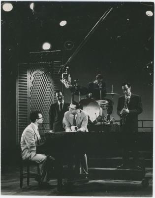 Dave Brubeck at piano, Steve Allen leaning on piano, with Bob Bates, Paul Desmond, and Joe Dodge on Steve Allen TV Show (New York City, New York)