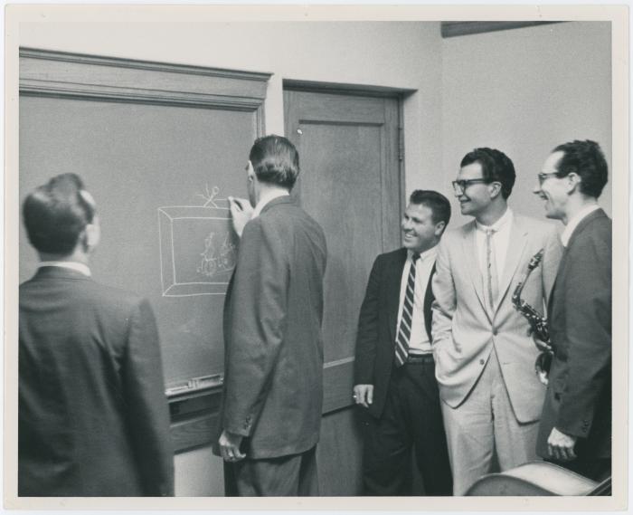 Dave Brubeck, Paul Desmond, Bob Bates, unidentified man, and Joe Dodge (writing on blackboard) (Denver, Colorado?)