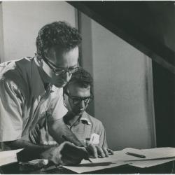 Dave Brubeck at piano, Paul Desmond standing at piano writing