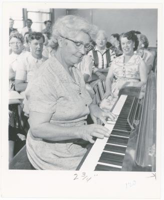 Mrs. Constance Blitz of Albany playing piano while class watches during a "Dave teaches teachers" session for Alameda County school teachers (California)