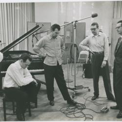 George Avakian and Fred Plant (smoking pipe, Columbia producer and recording engineer), with Norman Bates (seated), Dave Brubeck, Joe Morello, and Paul Desmond listening to playback #2 (New York City, New York [?])