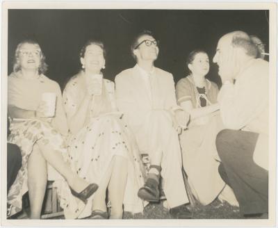 Dave Brubeck and Iola Brubeck (seated), George Avakian (kneeling), 2 unidentified women (seated) listening to concert at Newport Jazz Festival (Newport, Rhode Island)