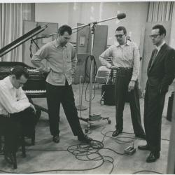 George Avakian and Fred Plant (smoking pipe, Columbia producer and recording engineer), with Norman Bates (seated), Dave Brubeck, Joe Morello, and Paul Desmond listening to playback #1 (New York City, New York [?])