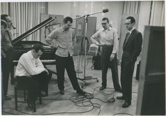 George Avakian and Fred Plant (smoking pipe, Columbia producer and recording engineer), with Norman Bates (seated), Dave Brubeck, Joe Morello, and Paul Desmond listening to playback #1 (New York City, New York [?])