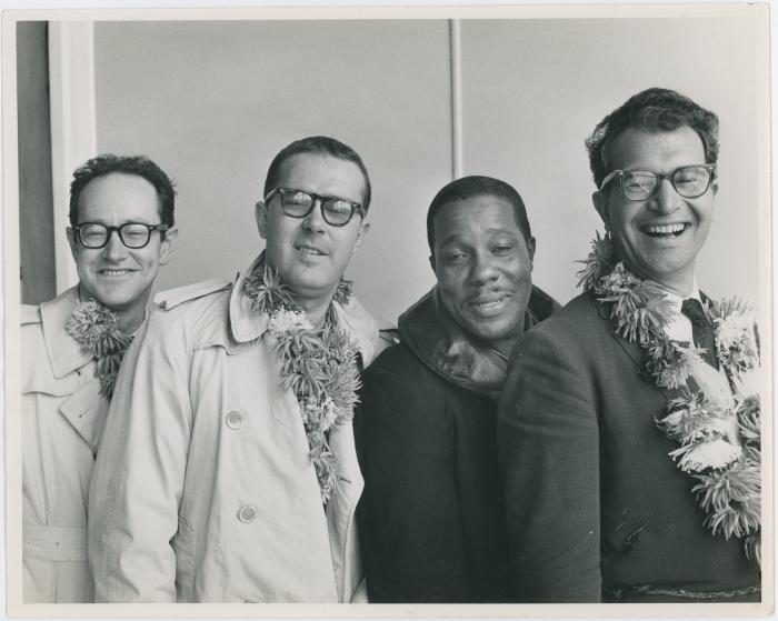 An exhausted looking Dave Brubeck Quartet (all wearing flower garland with the exception of Eugene Wright) at airport (Wellington, New Zealand)