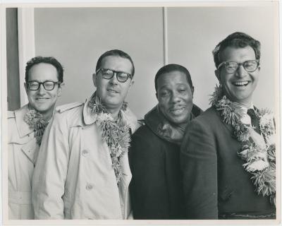 An exhausted looking Dave Brubeck Quartet (all wearing flower garland with the exception of Eugene Wright) at airport (Wellington, New Zealand)